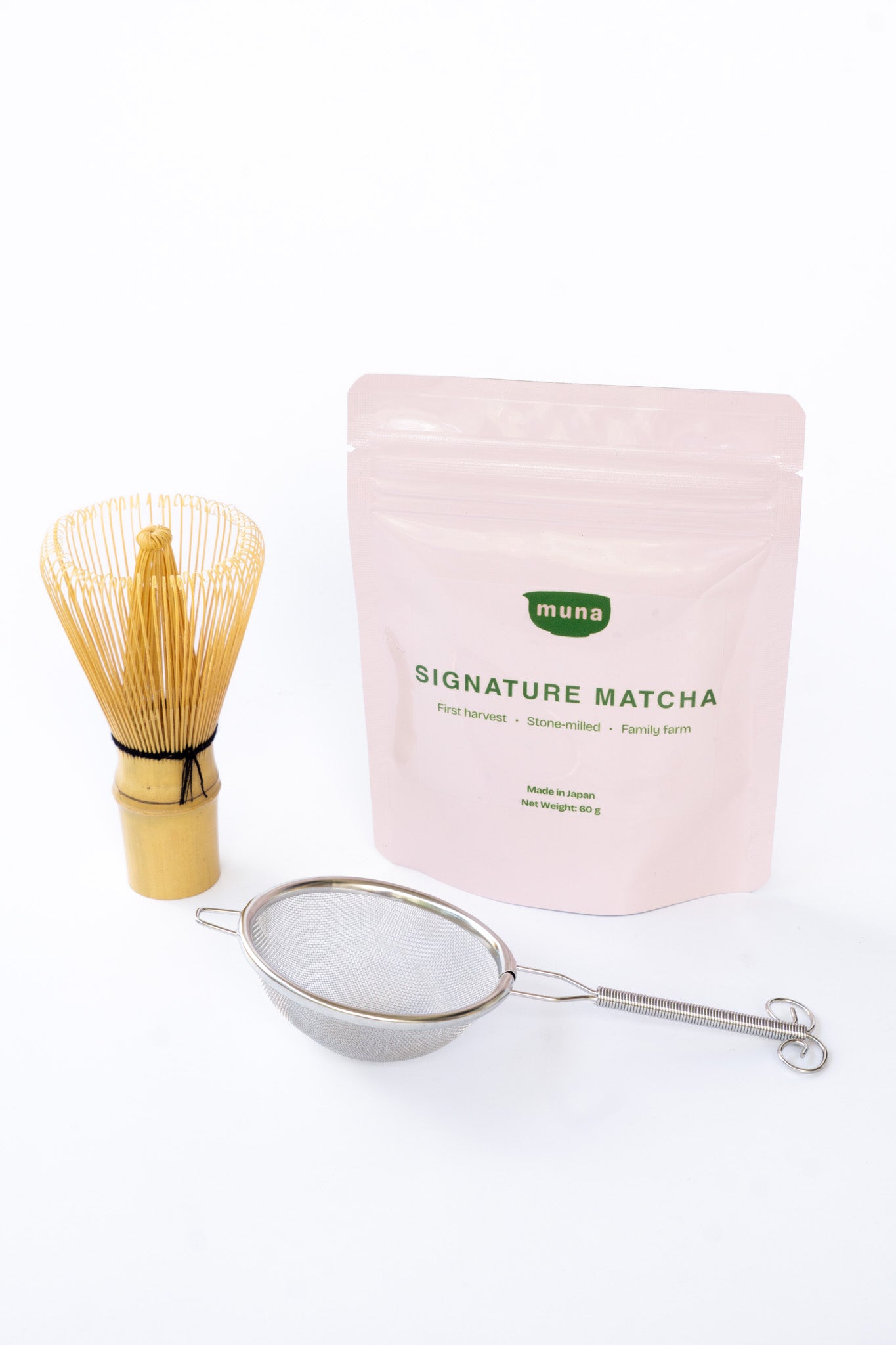 Muna Matcha Essentials Set of Signature Matcha, a whisk and a sieve on a white background