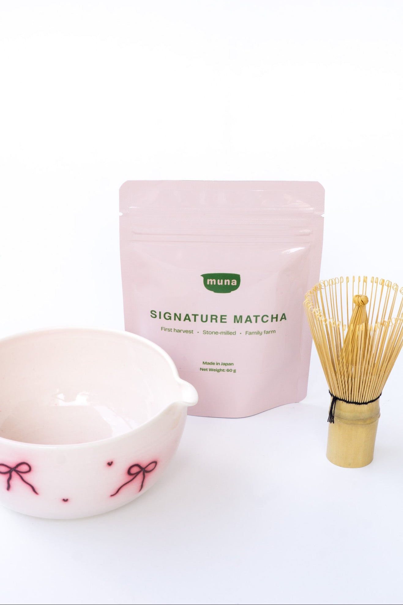 Muna Signature Matcha packaging with a ceramic bowl and whisk on a white background